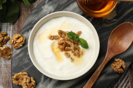 Delicious Greek yogurt with honey, nuts and mint on wooden table, flat layの写真素材