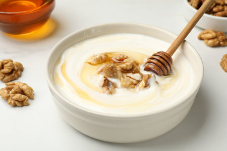 Delicious Greek yogurt with honey and nuts on white table, closeupの写真素材