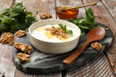 Delicious Greek yogurt with honey, nuts and mint on wooden tableの写真素材