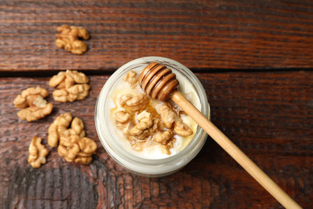 Delicious Greek yogurt with honey and nuts on wooden table, flat layの写真素材