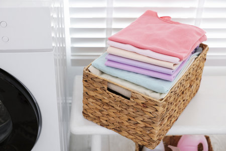 Laundry basket with clean folded clothes on bench indoors, closeupの写真素材