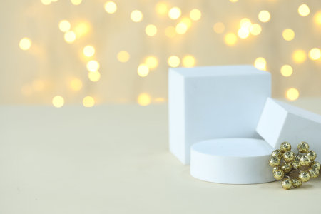 Empty podiums and Christmas decor on table against beige background with blurred lights, closeup with bokeh effect. Mockup for designの写真素材