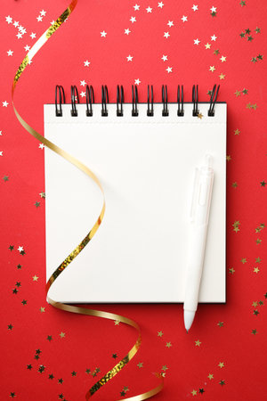 New Year aims. Planner, pen and festive decor on red background, flat layの写真素材