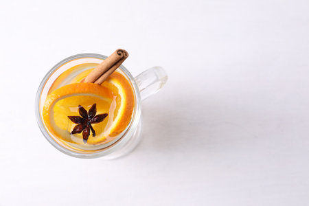 Tasty mulled wine with spices and orange slices in glass cup on white table, top view. Space for textの写真素材