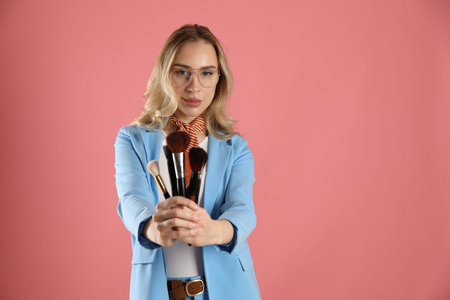Makeup artist with set of brushes on pink background, space for textの写真素材