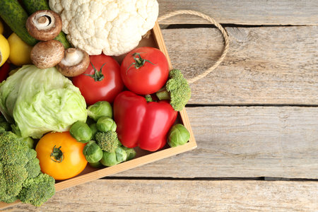 Different fresh raw vegetables and fruits in crate on wooden table, top view. Space for textの写真素材