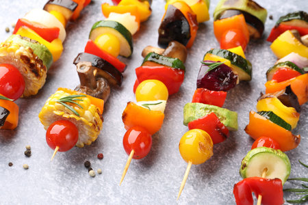 Skewers with tasty grilled vegetables on light textured table, closeupの写真素材