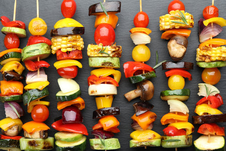 Skewers with tasty grilled vegetables on slate board, flat layの写真素材