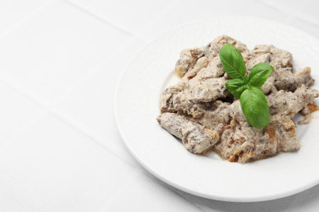 Tasty beef Stroganoff with basil on white tiled table, closeup. Space for textの写真素材