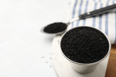 Aromatic black caraway in bowl and spoon on white table, closeup. Space for textの写真素材