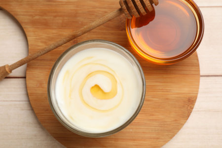 Delicious Greek yogurt with honey served on white wooden table, flat layの写真素材