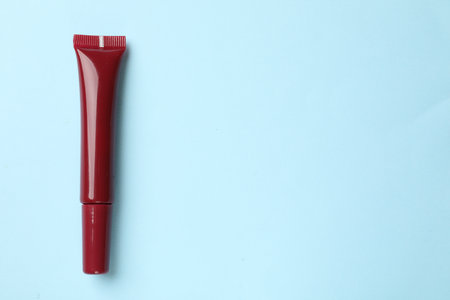 Beautiful dark red lip gloss on light blue background, top view. Space for textの写真素材