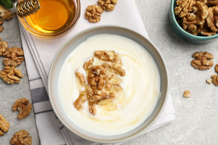 Delicious Greek yogurt with honey and nuts on light grey table, flat layの写真素材