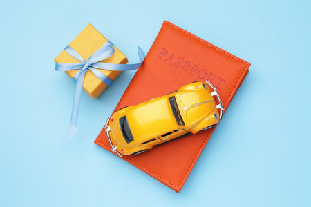 Christmas vacation. Passport, toy car and gift box on light blue background, flat layの写真素材