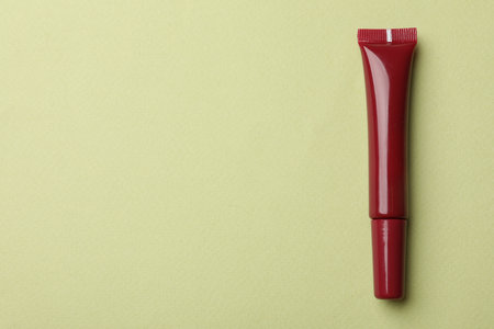 Beautiful dark red lip gloss on light green background, top view. Space for textの写真素材