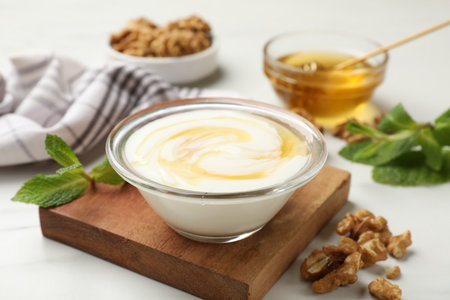 Greek yogurt with honey and walnuts served on white table, closeupの写真素材