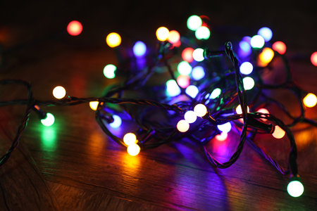 Bright Christmas lights on wooden table in darkness, closeupの写真素材