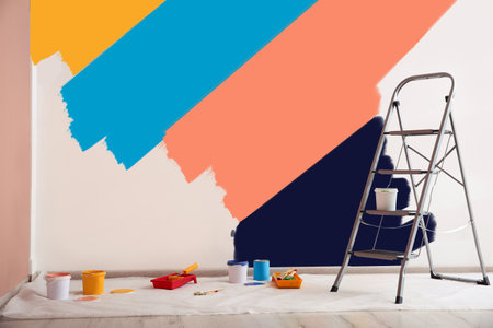 Decorator's stuff in room near wall partly painted in different shades. Choosing color for interiorの写真素材