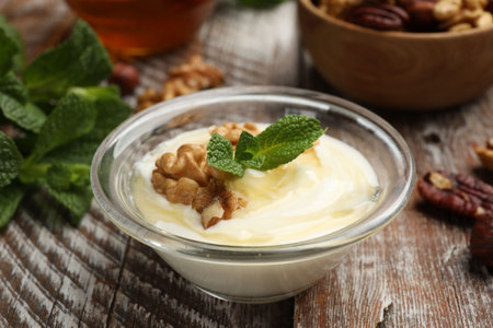 Delicious Greek yogurt with honey, nuts and mint on wooden table, closeupの写真素材