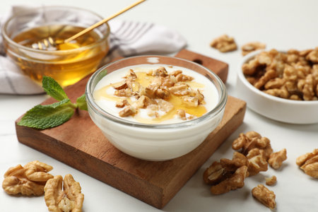 Delicious Greek yogurt with honey and walnuts served on white table, closeupの写真素材