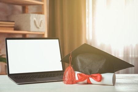 Diploma, graduation cap and laptop on white wooden table indoors, closeupの写真素材
