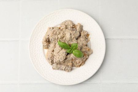 Tasty beef Stroganoff with basil on white tiled table, top viewの写真素材