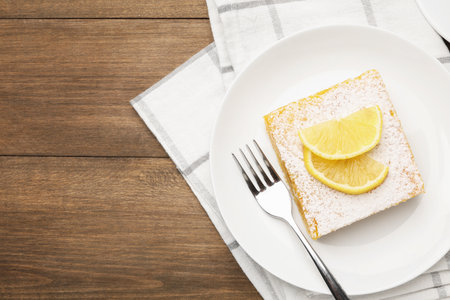 Tasty lemon bar with powdered sugar served on wooden table, flat lay. Space for textの写真素材