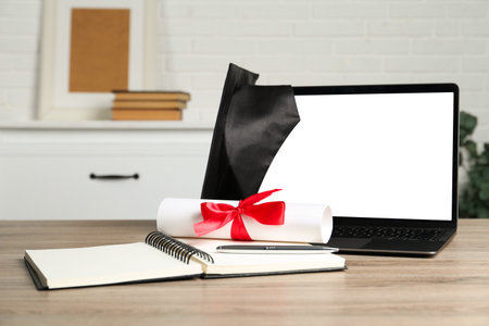 Diploma, notepad, pen and laptop on wooden table indoors, closeupの写真素材