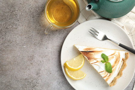 Slice of tasty lemon meringue tart with mint served on light gray table, flat lay. Space for textの写真素材