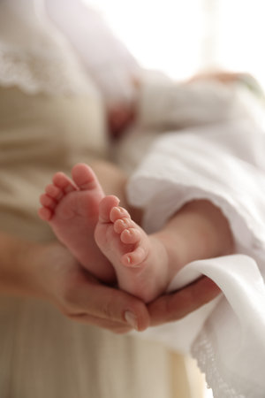 Sacrament of baptism. Woman holding little baby indoors, closeup