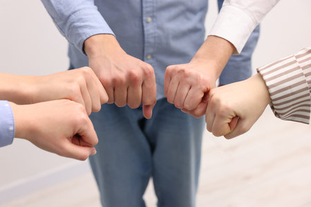 Team of volunteers bumping fists indoors, closeupの写真素材
