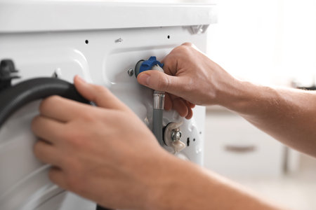 Repairman fixing broken washing machine at home, closeupの写真素材