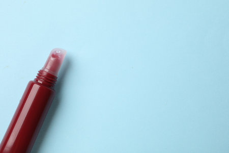Dark red lip gloss on light blue background, top view. Space for textの写真素材