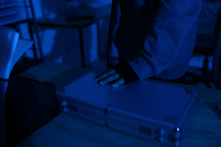 Thief trying to open locked briefcase with crowbar in office at night, closeupの写真素材
