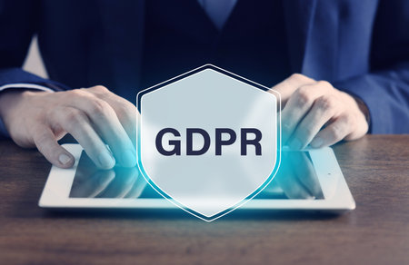 Man using tablet computer, closeup. Virtual shield with GDPR abbreviation. Privacy security