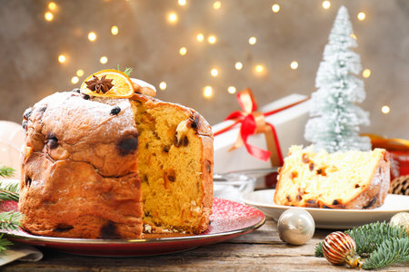 Tasty Christmas panettone cake with powdered sugar and festive decor on wooden table, closeupの写真素材