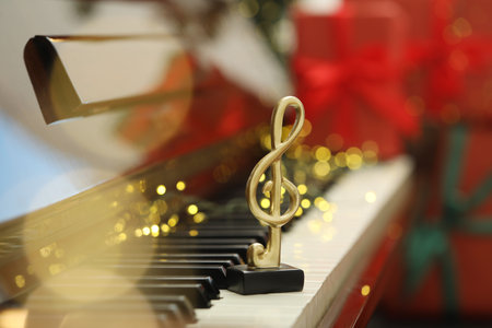 Christmas atmosphere. Golden treble clef on piano against blurred background, closeup with space for text. Bokeh effectの写真素材