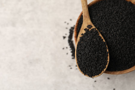 Aromatic black caraway in wooden bowl and spoon on light gray table, top view. Space for textの写真素材
