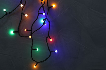 Bright Christmas lights on gray textured table, top view. Space for text