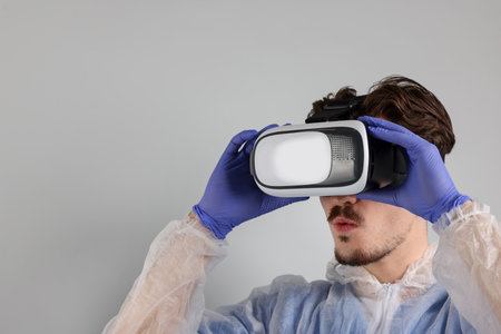 Modern technology. Doctor using virtual reality headset on gray background. Space for text