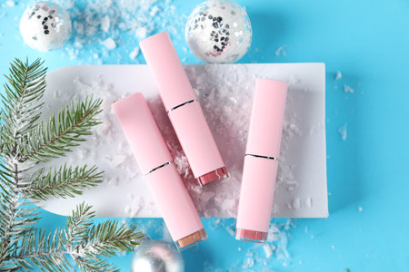 Stylish presentation of lipsticks and Christmas decor on light blue background, flat layの写真素材