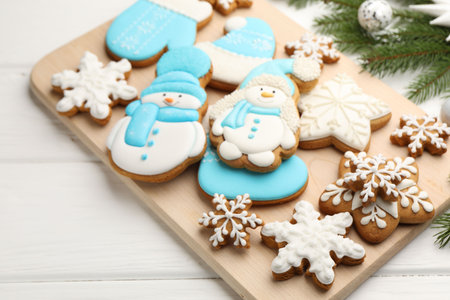 Tasty gingerbread cookies and Christmas decor on white wooden table, closeup