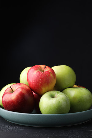 Fresh red and green apples on dark textured table against black background, closeup. Space for textの写真素材