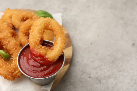 Deep fried squid rings with basil and ketchup on light gray table, closeup. Space for textの写真素材