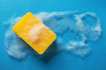 Kitchen sponge with foam on light blue background, top viewの写真素材