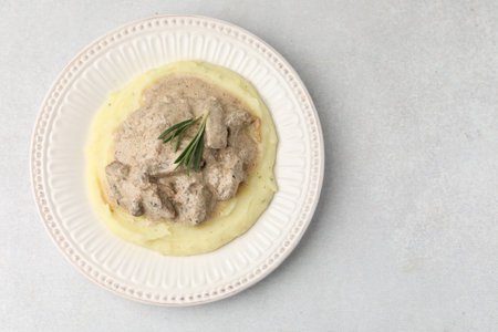 Delicious beef stroganoff with mashed potatoes and rosemary on light table, top view. Space for textの写真素材