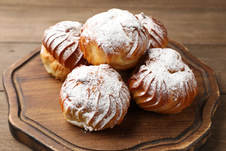 Tasty profiteroles with powdered sugar on wooden table, closeupの写真素材