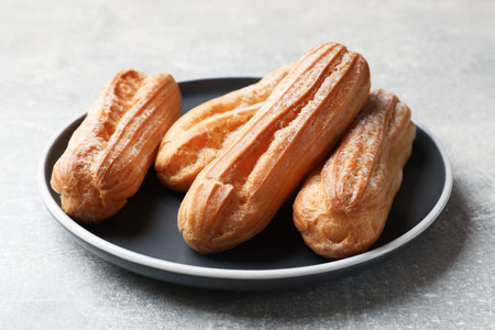 Delicious eclairs on light gray table, closeup