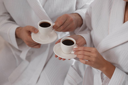Couple in bathrobes with morning coffee on bed indoors, closeupの写真素材