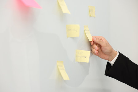 Man near whiteboard with sticky notes in office, closeup